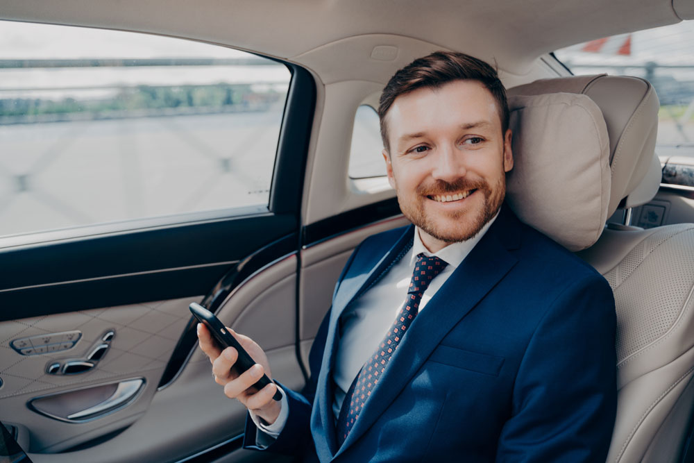 Man in the back of a luxury car travelling on business